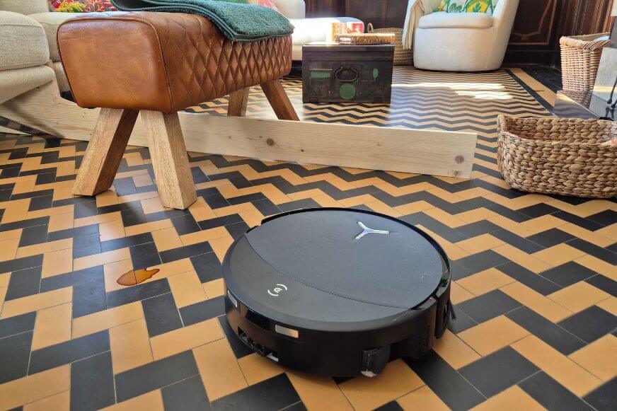 ecovacs-deebot-t90-pro-omni-fliesenboden-wohnzimmer-test Image alt: ECOVACS DEEBOT T90 PRO OMNI Saugroboter auf gemustertem Fliesenboden im Wohnzimmer. Praxistest beim Netzwelt First Look Event.